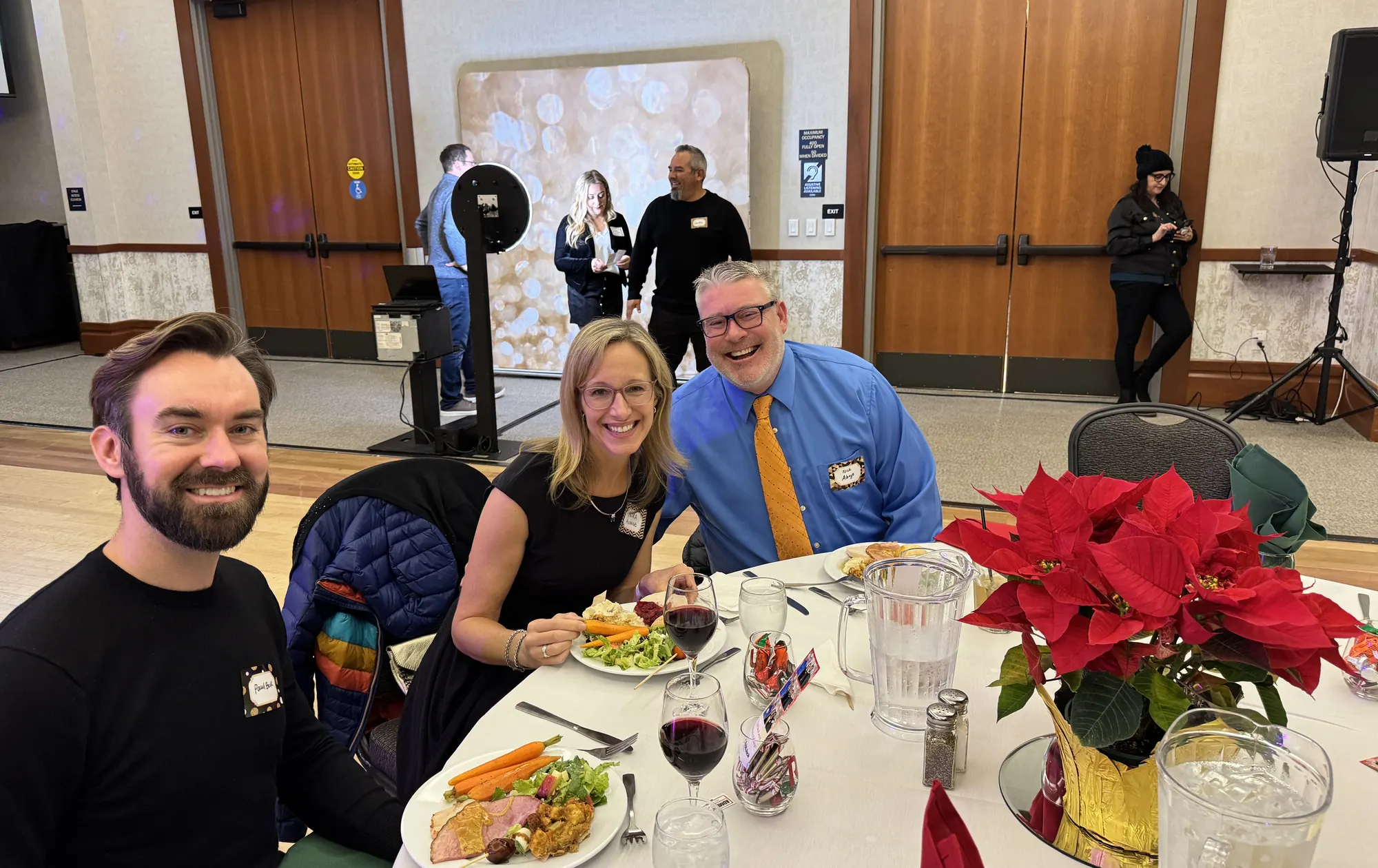 Three people laughing together at a table at the RobbJack Christmas party.